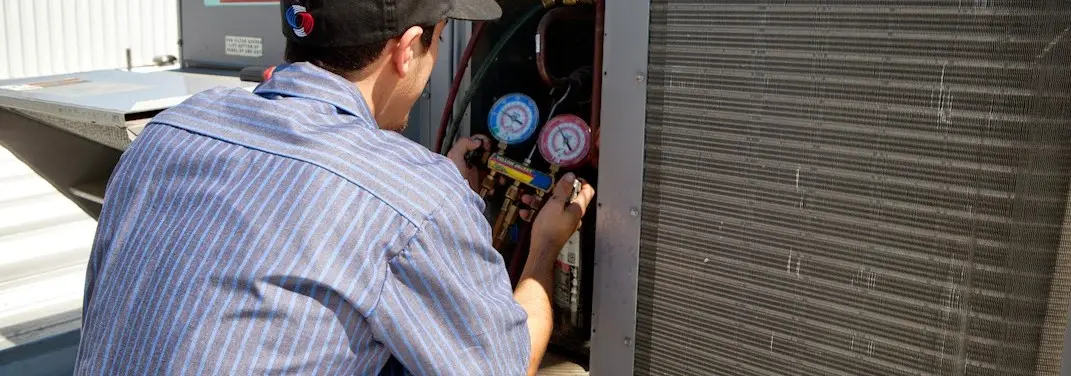 HVAC technician servicing a condenser unit in Melvindale